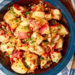 german potato salad recipe with bacon in a wooden serving bowl garnished with fresh parsley