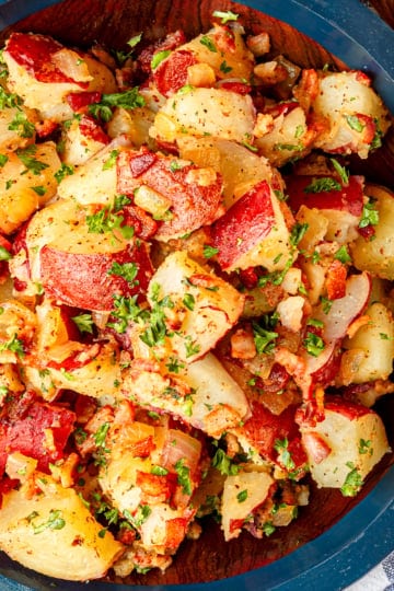 german potato salad recipe with bacon in a wooden serving bowl garnished with fresh parsley