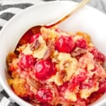 cherry pineapple dump cake recipe in a white bowl with a black and white towel