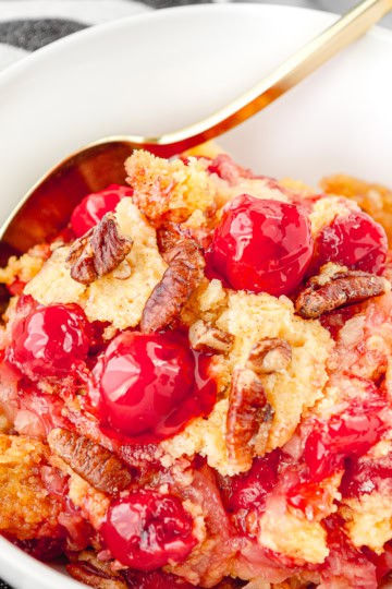 cherry pineapple dump cake recipe in a white bowl with a black and white towel