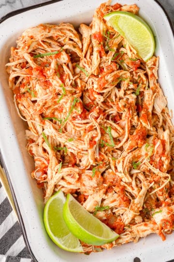easy salsa chicken recipe garnished with cut limes in a white enamel dish