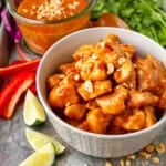 easy peanut butter chicken recipe in a bowl topped with chopped unsalted roasted peanuts
