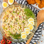 macaroni salad with egg recipe in a glass bowl garnished with hard boiled eggs and fresh dill