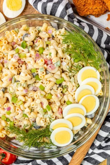 macaroni salad with egg recipe in a glass bowl garnished with hard boiled eggs and fresh dill