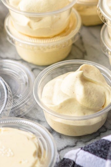 rumchata pudding shots in plastic shot cups with lids with a black and white kitchen towel