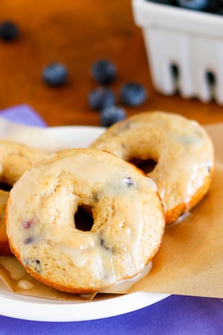 glazed baked blueberry donuts on brown parchment paper with fresh blueberries