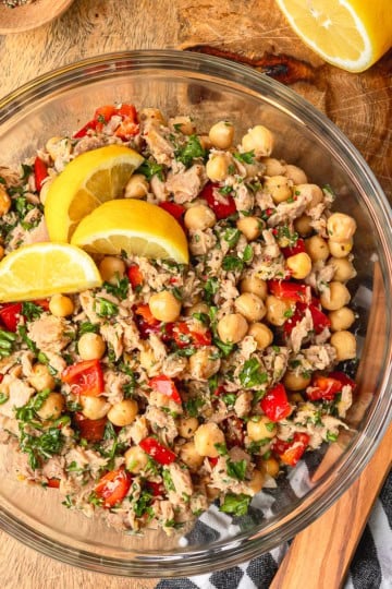 chickpea tuna salad recipe in a glass bowl on a wooden cutting board with lemon garnish