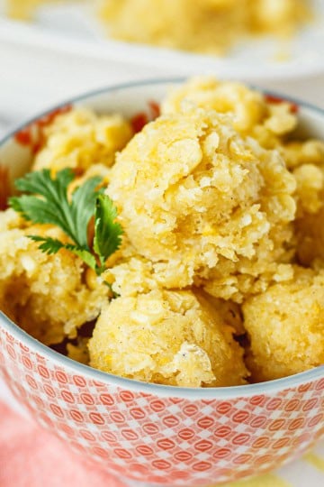 Chi-Chi's corn cake recipe scooped into an orange and white bowl with a silver spoon next to it