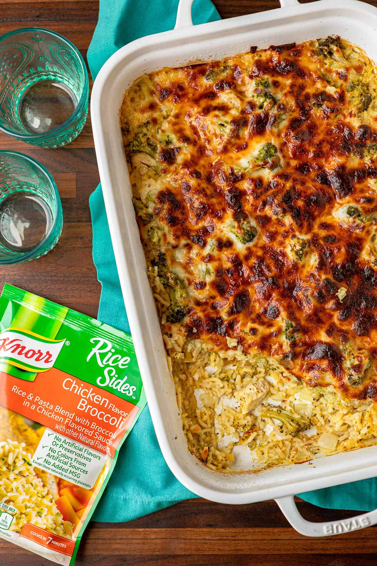 broccoli rice cheese and chicken casserole recipe in a white ceramic baking dish with two teal glasses on the side