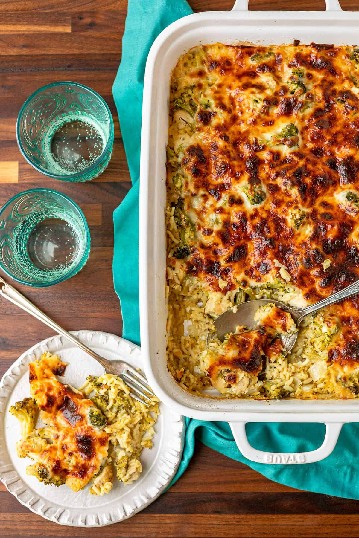 cheesy chicken broccoli and rice casserole in a white ceramic baking dish and on a plate with a fork