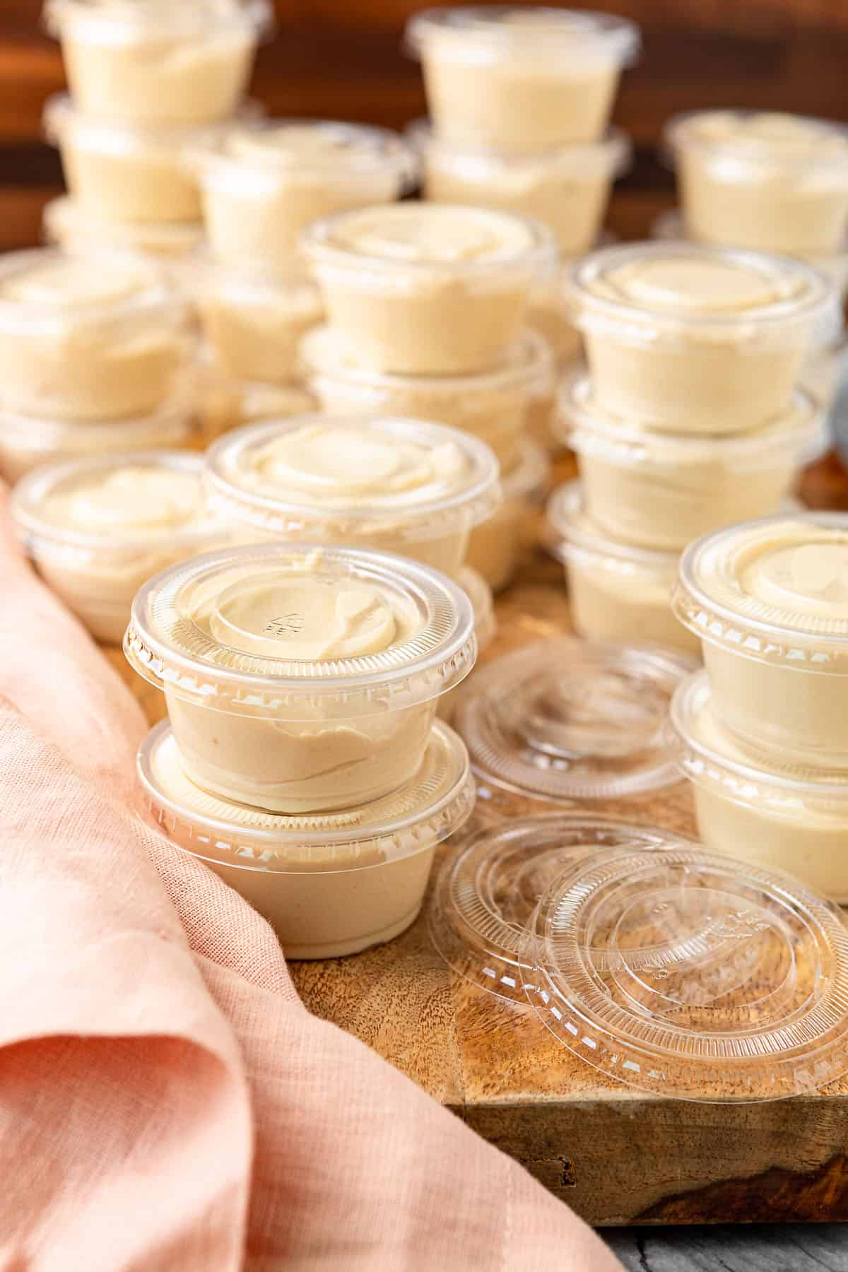 kahlua pudding shots in condiment cups with lids stacked on a wooden cutting board