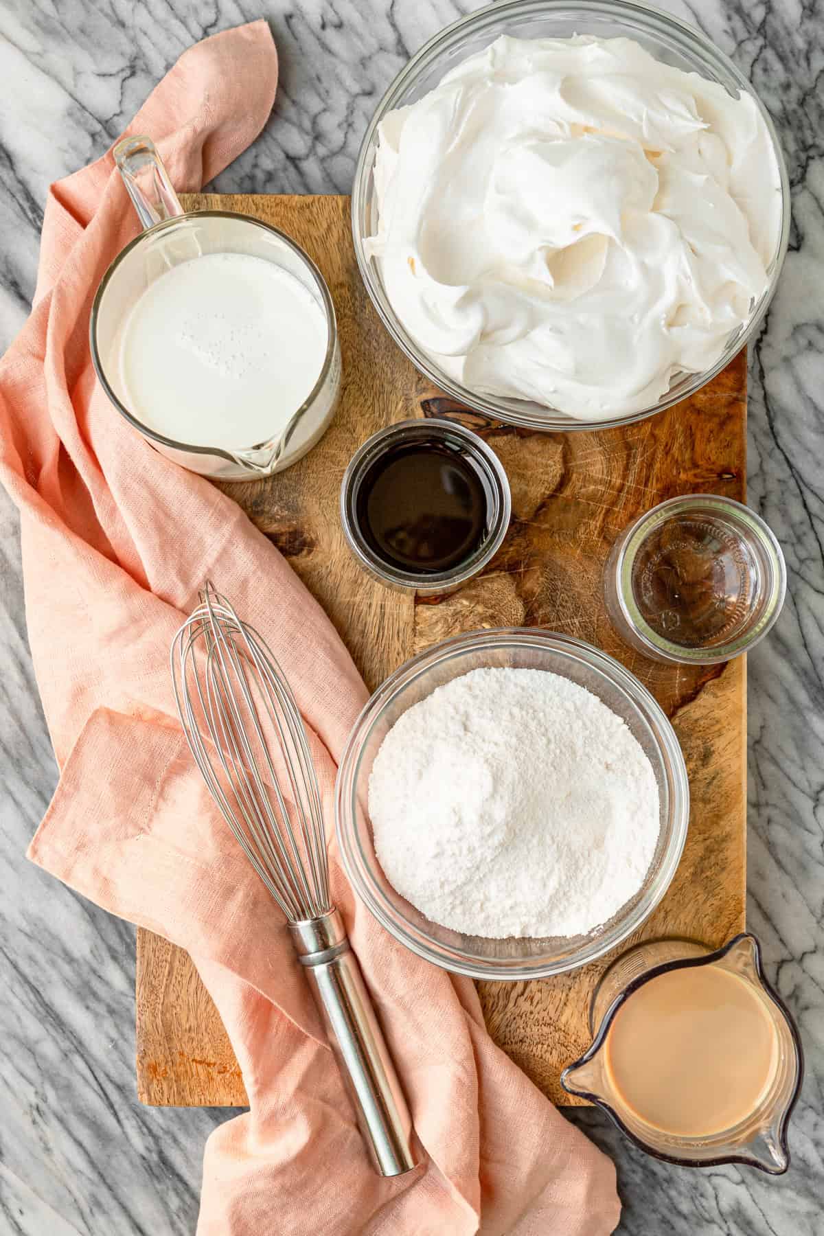 white russian kahlua pudding shots ingredients on a wood cutting board with a whisk