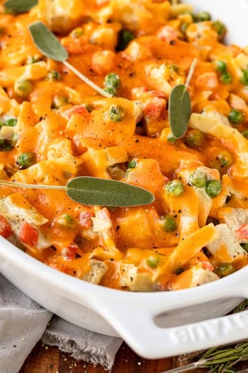 turkey noodle casserole recipe garnished with fresh sage in a white casserole dish