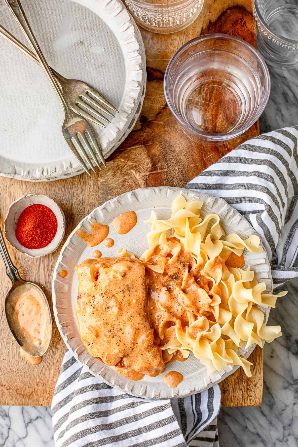 sour cream pork chops with egg noodles on a white ceramic plate with a striped napkin