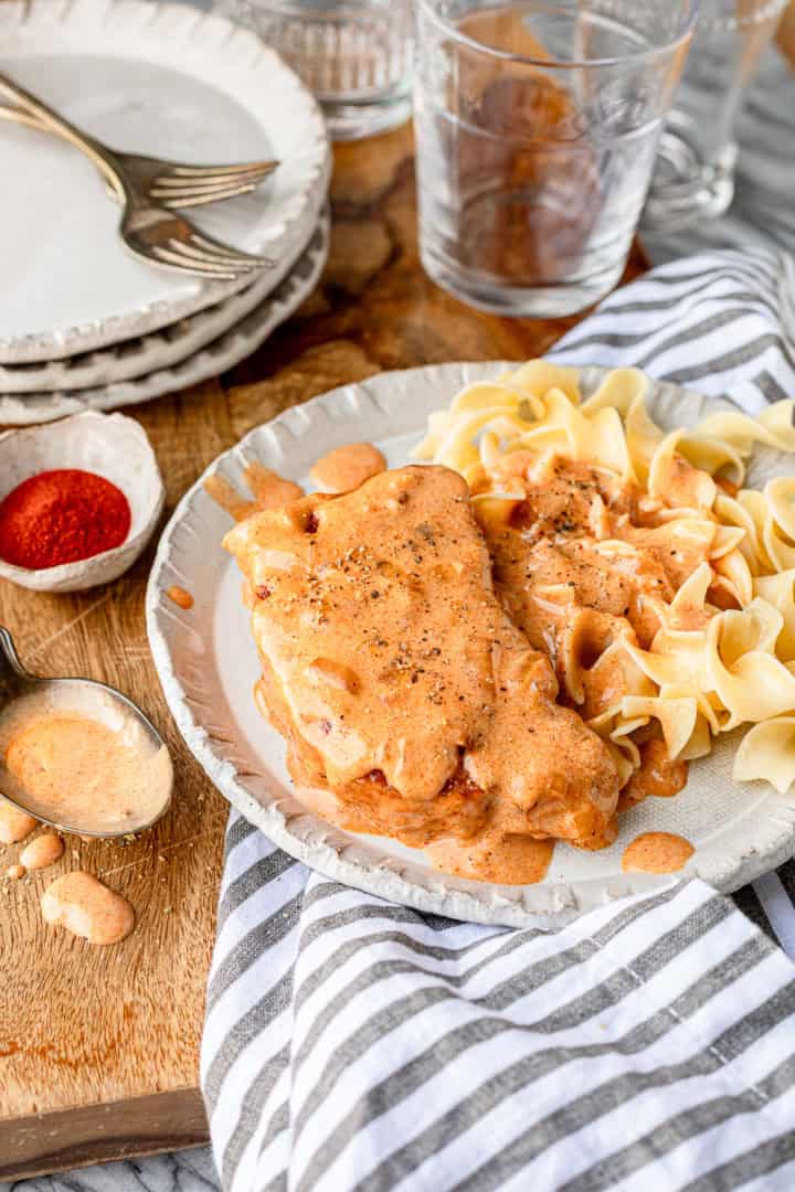 sour cream pork chops served over eggs noodles with a striped napkin