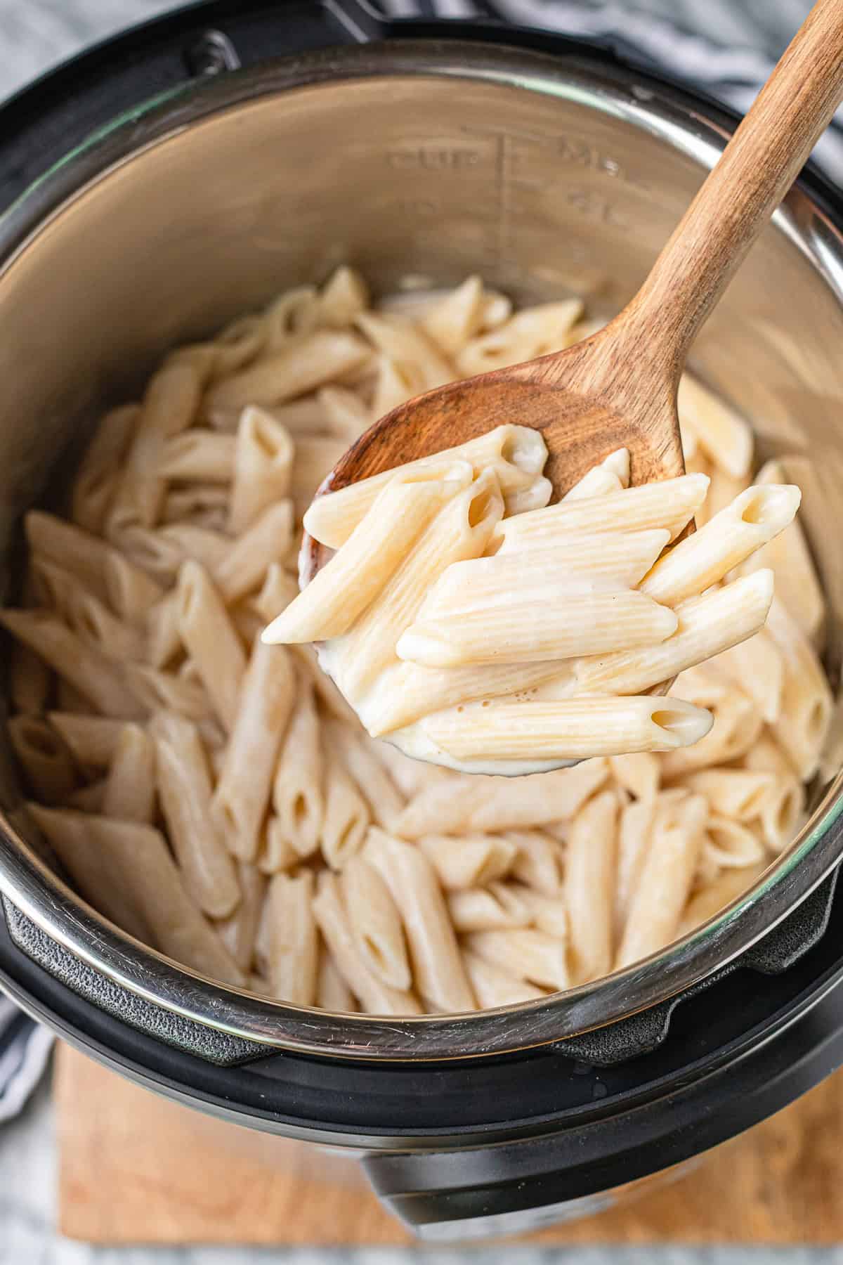 cheese sauce recipe for pasta in the instant pot with a wooden serving spoon scooping it out
