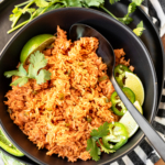 instant pot mexican rice recipe in a black ceramic bowl garnished with cilantro and sliced jalapeño peppers