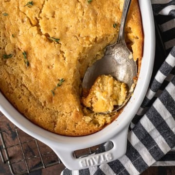 jiffy corn casserole recipe in a ceramic baking dish with a silver spoon