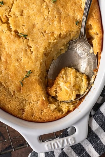 jiffy corn casserole recipe in a ceramic baking dish with a silver spoon