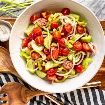 marinated tomato salad recipe in a white ceramic bowl with a black and white striped kitchen towel