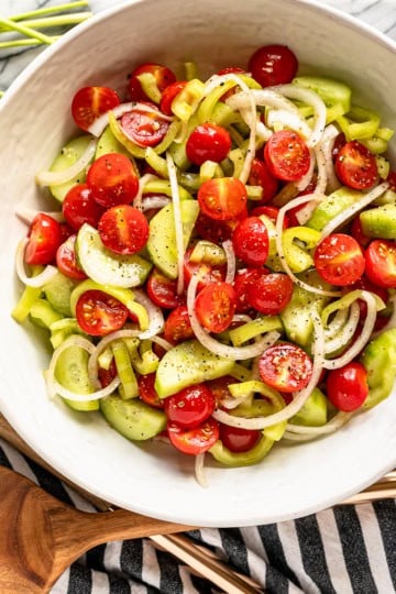 marinated tomato salad recipe in a white ceramic bowl with a black and white striped kitchen towel