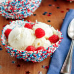 chocolate bowl filled with vanilla ice cream and fresh raspberries with a silver spoon