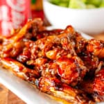 coca cola chicken wings piled up on a white ceramic platter
