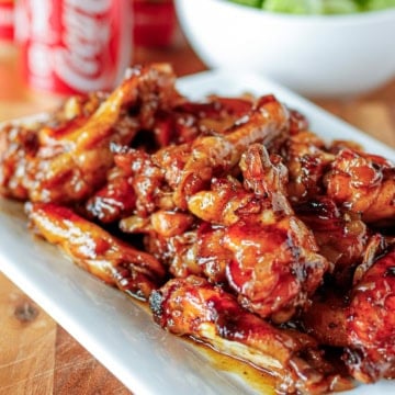 coca cola chicken wings piled up on a white ceramic platter
