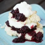 easy shortcake topped with blackberry sauce and whipped cream on a teal plate