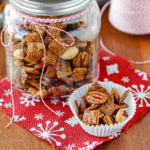 gingerbread chex mix in a glass jar sitting on a festive red and white scrap of burlap