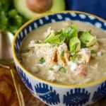 chili chicken verde in a blue and white bowl topped with dice avocado and cilantro