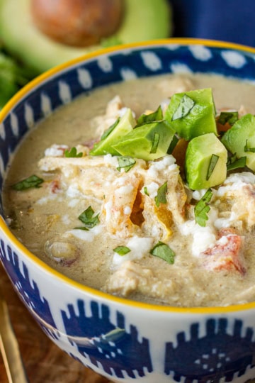 instant pot chili chicken verde in a blue and white bowl topped with dice avocado and cilantro