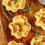 mini ham and cheese quiche on a wooden cutting board with fresh thyme