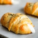 crescent pizza rolls topped with Italian seasoning on parchment paper