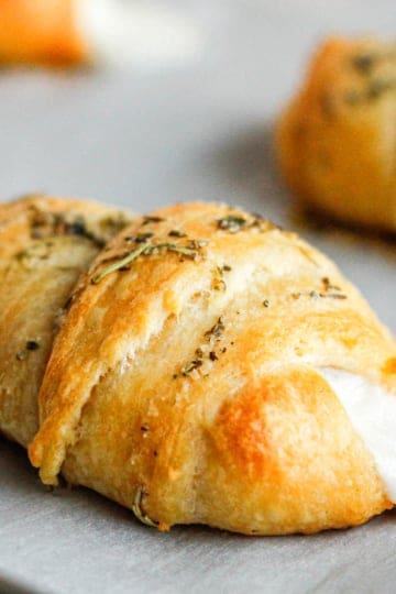 crescent pizza rolls topped with Italian seasoning on parchment paper