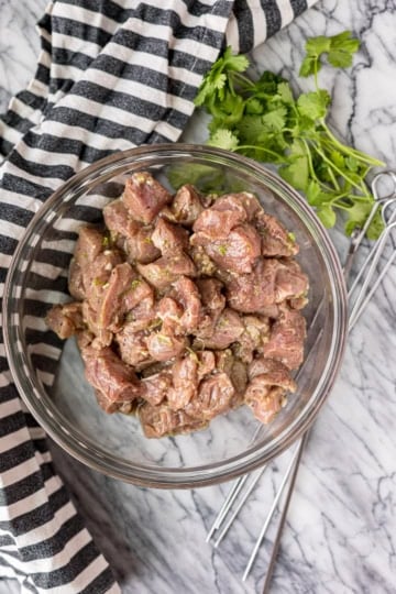 pork tenderloin cubes in garlic lime pork kabob marinade in a glass bowl