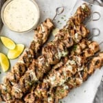 honey garlic lime grilled pork kabobs with metal skewers on a parchment paper lined baking sheet