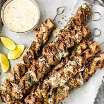 honey garlic lime grilled pork kabobs with metal skewers on a parchment paper lined baking sheet