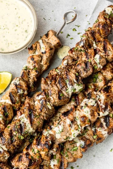 honey garlic lime grilled pork kabobs with metal skewers on a parchment paper lined baking sheet