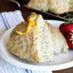 glazed lemon poppy seed scones on a white ceramic plate with fresh strawberries