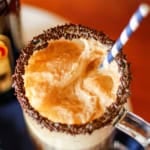 root beer float cocktail with a blue and white straw and chocolate sprinkles