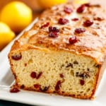 cranberry lemon bread sliced on a white ceramic platter