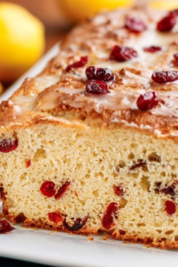cranberry lemon bread sliced on a white ceramic platter