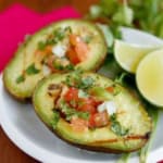 grilled avocado with pico de gallo on a white ceramic dish