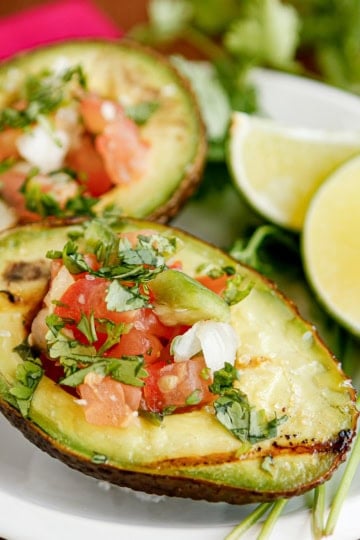 grilled avocado with pico de gallo on a white ceramic dish