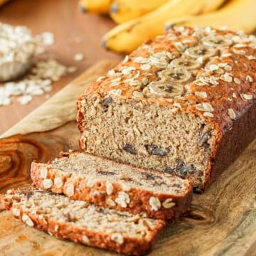 oatmeal banana bread with pecans sliced on a wooden cutting board