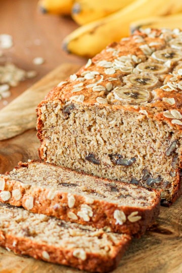 oatmeal banana bread with pecans sliced on a wooden cutting board