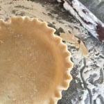 pie crust recipe using crisco dough in a pie plate with crimped edges and flour sprinkled around