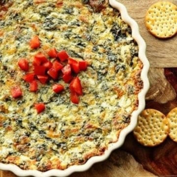 olive garden spinach artichoke dip in a baking dish garnished with diced red peppers