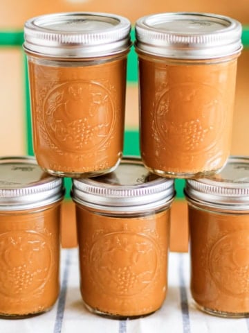sweetened milk caramel in glass canning jars with lids stacked on a wood table